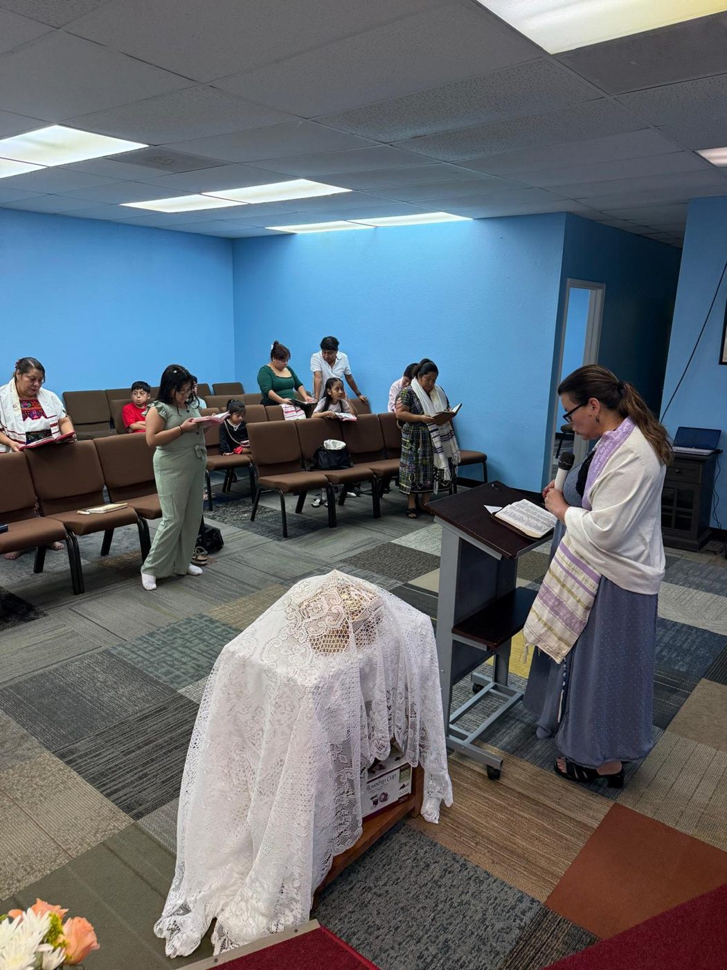 Una ministra lee la Biblia desde el púlpito mientras la congregación sigue la lectura